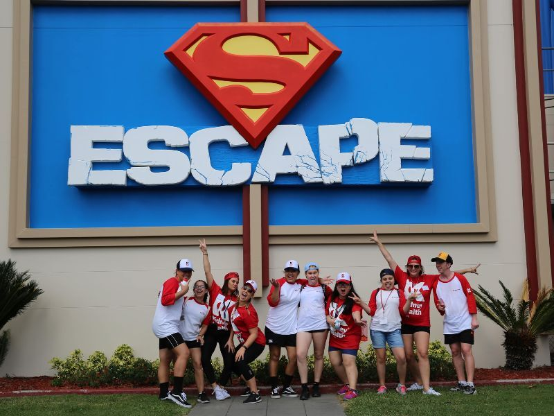 A group of kids pose for a photo in front of the Escape sign