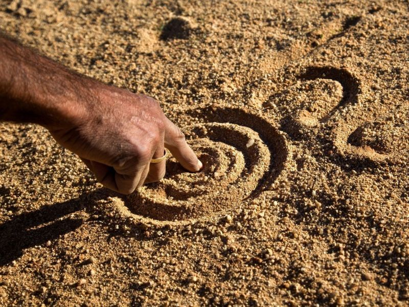 Aboriginal drawings in sand with action hand