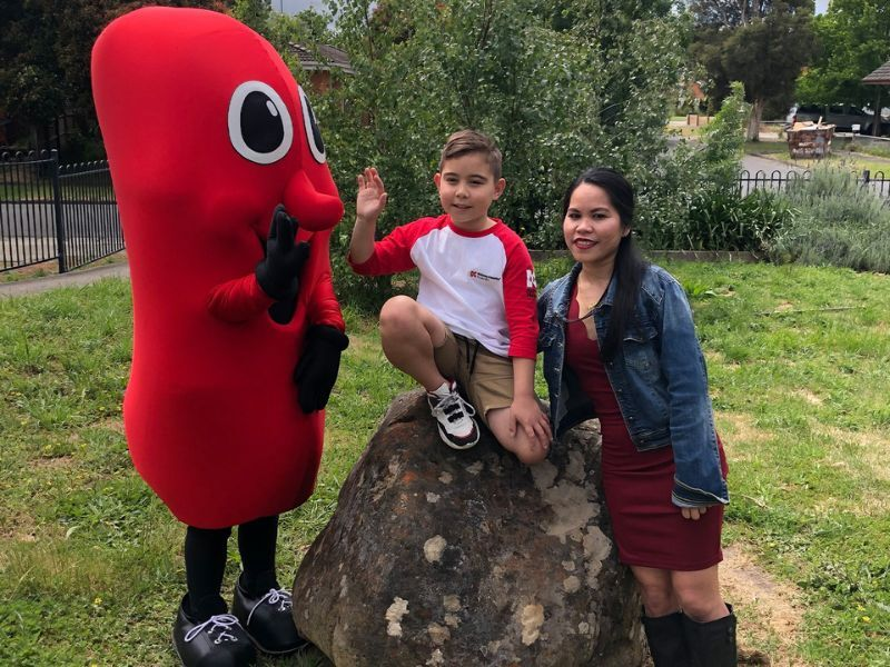 A young boy and his mother pose by the Kidney Health mascot