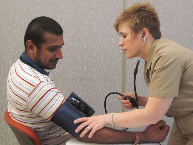 A female health professional measures a man's blood pressure