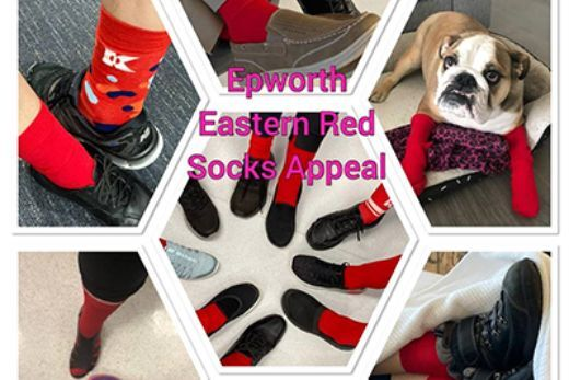 Epworth staff pose for a photo with their feet in red socks and a bulldog wearing red socks