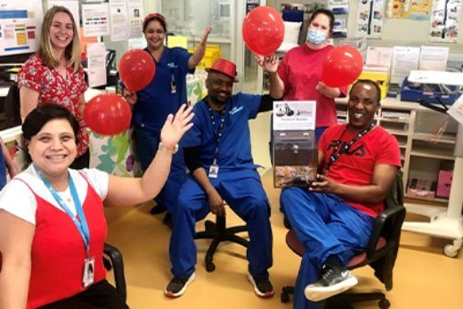 Tuggeranong staff pose for a photo with red balloons