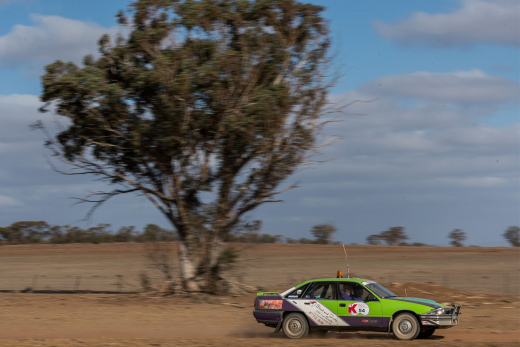 A green car racing through the desert in the Kidney Kar Rally