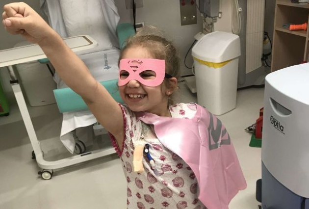 Aleia smiles while wearing a pink mask and cape