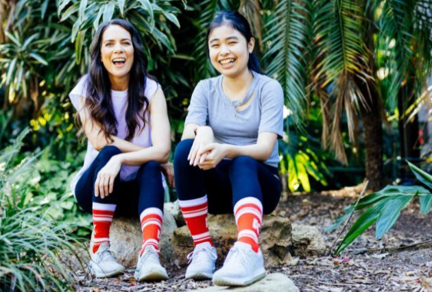 Two women smiling and wearing red socks