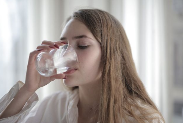 A young woman drinking a glass of water