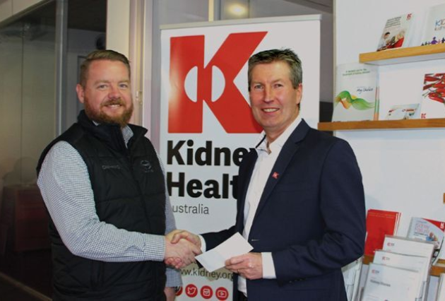 Two men shake hands in front of a kidney health australia banner