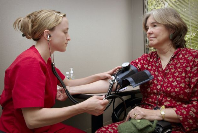 A female health professional takes the blood pressure of a woman