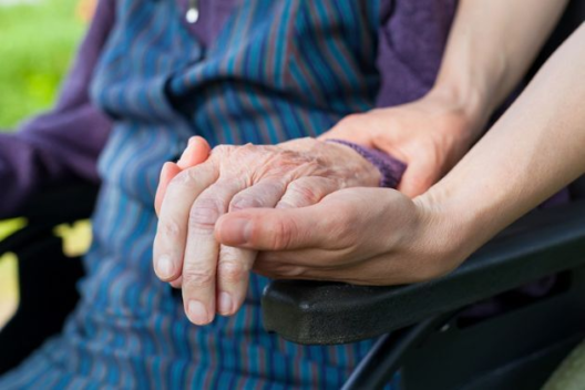 A young woman holds an older woman's hand