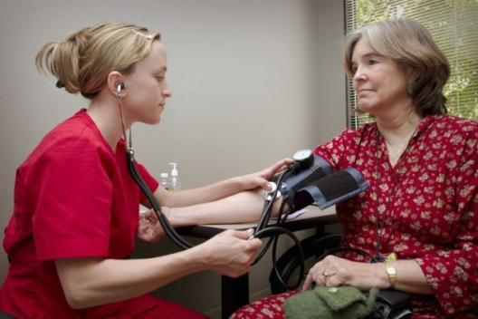 A female health professional takes the blood pressure of a woman