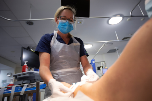 Renal nurse applying tape to arm of woman on dialysis